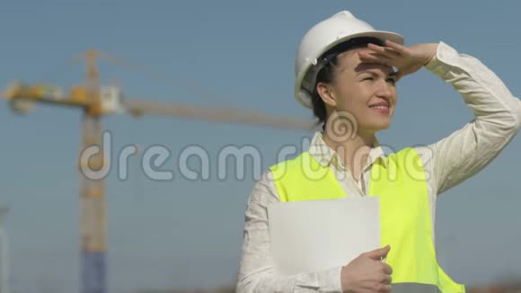 穿着防护服的女建筑工人用手做了一个面罩看着远处女人在微笑视频的预览图