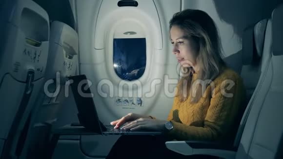漂亮的女人正在飞机舱里的笔记本电脑上打字在飞机里工作的女乘客视频的预览图