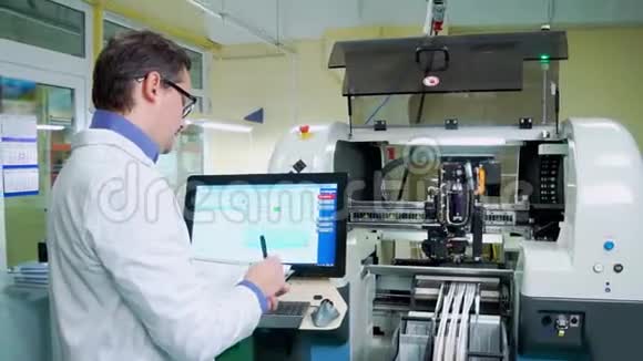 工程师穿着白色长袍和眼镜为表面安装技术机器工作数控机床Pcb加工视频的预览图