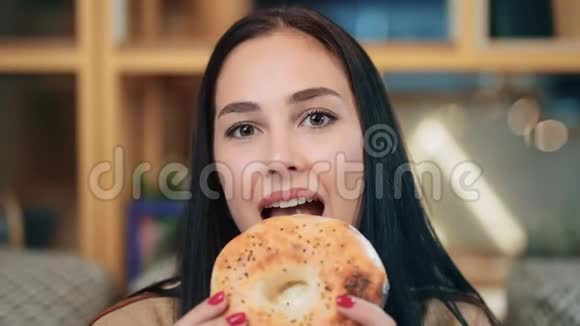 可爱的黑发女人咬着面包咀嚼享受味道的肖像近距离拍摄4k红色相机视频的预览图