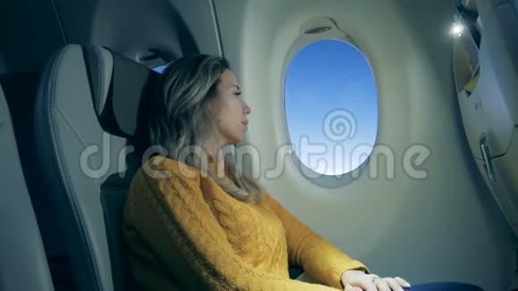 一个女人正在透过飞机窗户看坐飞机的女孩用笔记本电脑视频的预览图