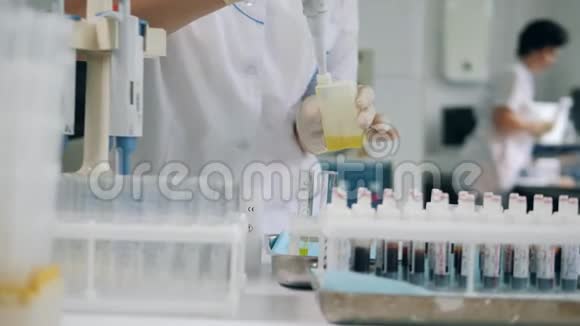 在实验室做冠状病毒样本的科学家黄色液体倒入试管视频的预览图