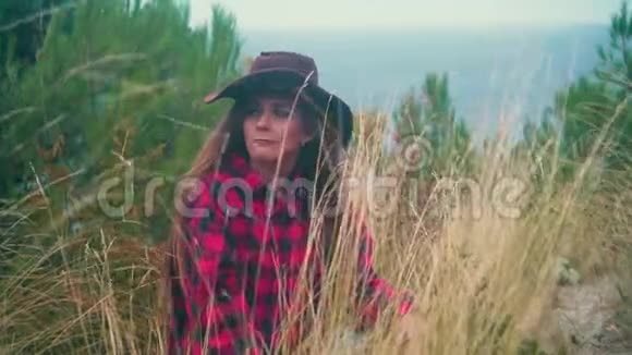 一个长发女孩的肖像穿着黑色和红色的衬衫戴着牛仔帽坐在干草里视频的预览图