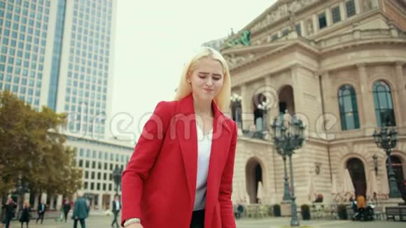 穿红色夹克的金发美女拿起一个沉重的大包视频的预览图