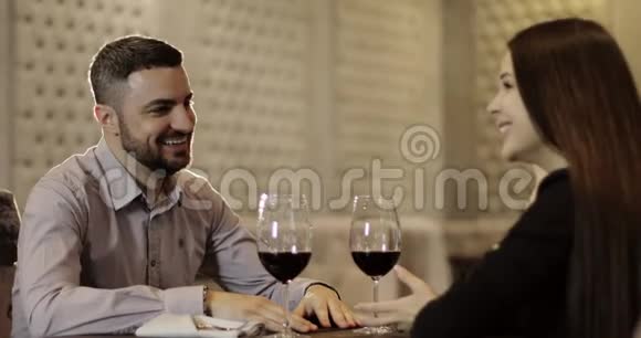 布鲁内特女士和胡子男正坐在餐厅的桌子旁喝红酒视频的预览图