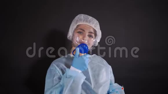 穿着防护服的年轻女子在带有食用阀的防护医疗面罩上双手是视频的预览图