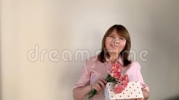 贴身女人捧着一束粉红色的康乃馨花盒子里的礼物微笑节日的概念女人日母亲视频的预览图