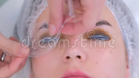美容师覆盖女性睫毛档案垫和毛巾提升睫毛程序视频的预览图