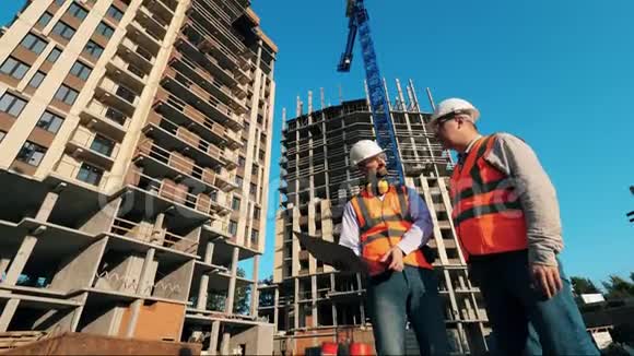两名工人站在建筑物附近检查他们施工承包商在施工现场工作视频的预览图
