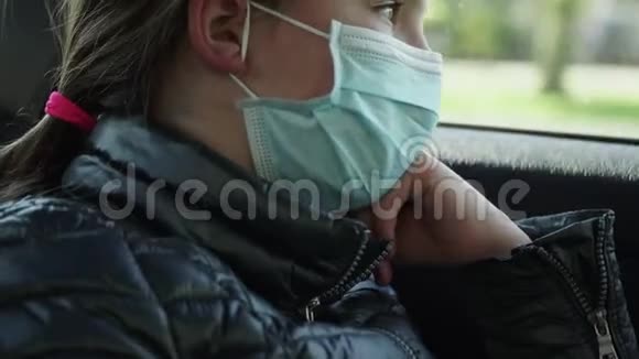 戴口罩的无聊的小女孩坐在汽车后座上检疫概念3视频的预览图