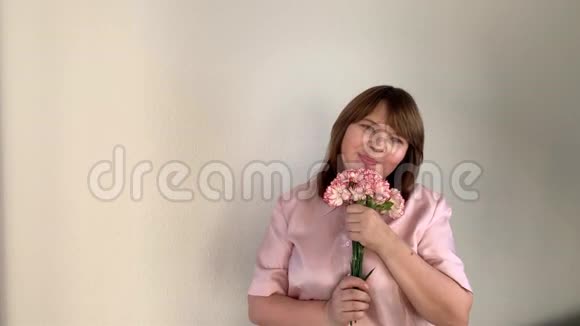 女人捧着一束粉红色的康乃馨带着喜悦的微笑节日的概念女人日子母亲视频的预览图