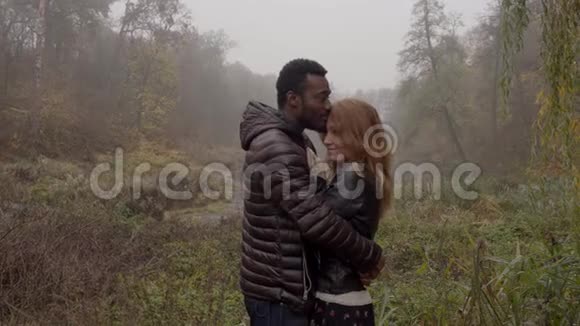 种族间的爱情观念在雾蒙蒙的秋天公园里摆姿势的一对年轻的混血儿视频的预览图