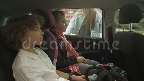 美丽的成年母亲为十几岁的女儿和儿子打开车门在他们去之前吻别视频的预览图