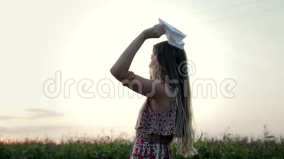一位年轻女子在一片绿色的田野上举起一架纸飞机飞向蓝天追随梦想的概念视频的预览图