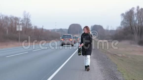 一个走在公路边上的女孩手里拿着一个黑色的防毒面具视频的预览图
