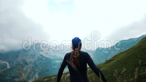 留着长发的徒步旅行者在山上举起双手欣赏美丽的的野生自然胜利和胜利视频的预览图
