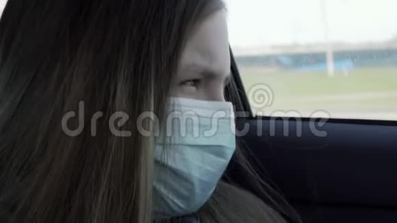 隔离概念戴口罩的恶心的小女孩坐在汽车后座上戴防护口罩的伤心女孩视频的预览图