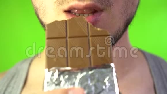有胡子的男人嘴咬着一块巧克力巧克力和甜食的概念喜欢吃巧克力的人视频的预览图