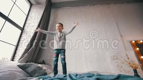 快乐而微笑的男孩在床上蹦蹦跳跳地抓住一只玩具熊视频的预览图