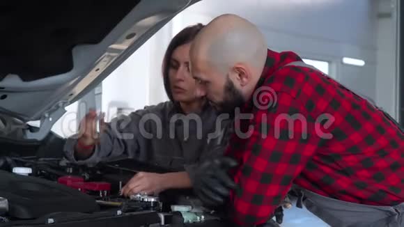 两名专业技工男女在汽车修理厂修理一辆汽车汽车服务维修和保养视频的预览图