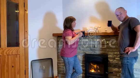 男人和女人在壁炉边喝茶聊天概念是一个舒适的家爱情浪漫视频的预览图
