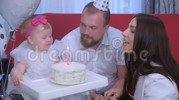 家庭肖像妈妈爸爸和小女孩在一岁生日蛋糕和蜡烛视频的预览图