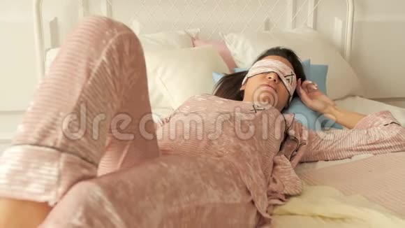 女孩在床上打盹戴着睡眠面具闭着脸梦想在粉红色睡衣卧室4K视频的预览图
