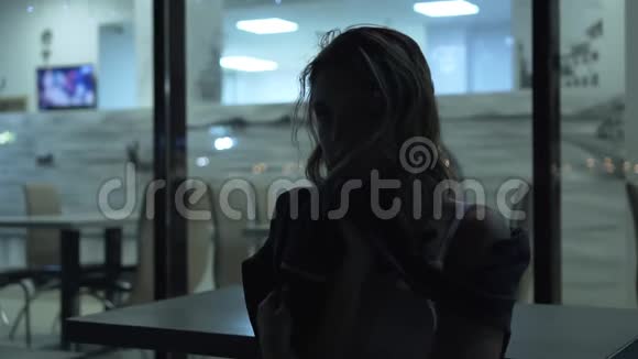 一个孤独而悲伤的女孩在一个明亮的橱窗的背景下写字视频的预览图