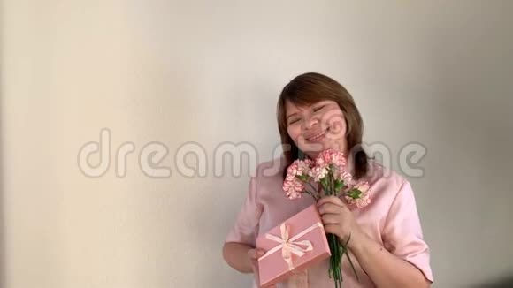 贴身女人捧着一束粉红色的康乃馨花盒子里的礼物微笑节日的概念情人节妈妈视频的预览图