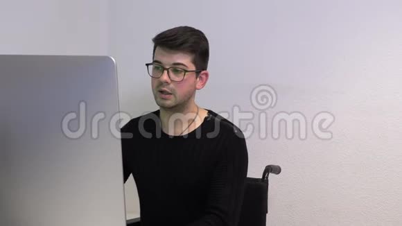 办公室经理坐在轮椅上一位黑发男子在电脑附近的工作场所举行了一次在线会议视频的预览图