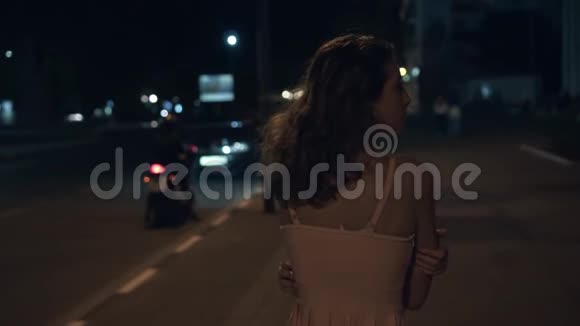 一个孤独的女孩在晚上绕着城市走旋转环顾四周视频的预览图