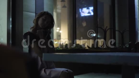 一个孤独而悲伤的女孩在一个明亮的橱窗的背景下写字视频的预览图