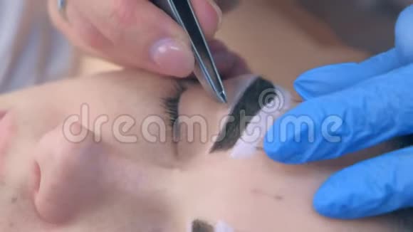 美容师用镊子给美容院的女人拔眉毛视频的预览图