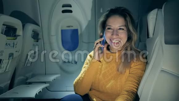 美丽的女人在飞机上打电话时很开心视频的预览图