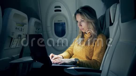 女性自由职业者在坐飞机的笔记本电脑上工作一位女士在一台笔记本电脑上工作时半暗视频的预览图