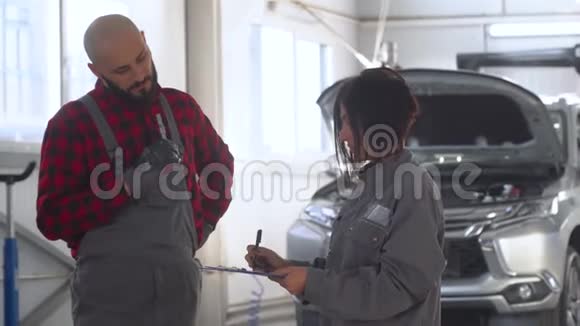 汽车修理车间两名专业技工男女汽车服务维修和保养视频的预览图