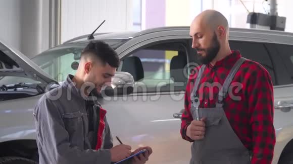 两名专业机械师在汽车修理厂修理一辆汽车汽车服务维修和保养视频的预览图