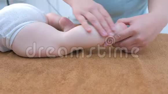 专业医生按摩师在诊所为婴儿做腿部按摩特写视频的预览图