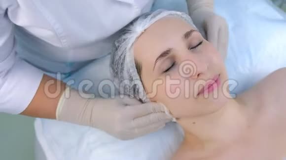 美容师在美容诊所用棉垫擦拭女人脸特写视频的预览图