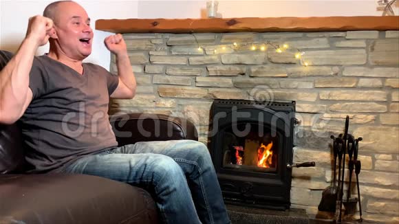 中年男子坐在一块石头旁边的皮革沙发上享受着温暖有感情地跳舞微笑一个美好的概念视频的预览图