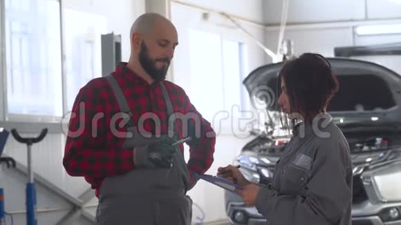 汽车修理车间两名专业技工男女汽车服务维修和保养视频的预览图