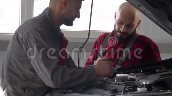 两名专业机械师在汽车修理厂修理一辆汽车汽车服务维修和保养视频的预览图