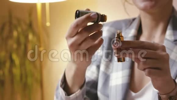 一位美丽的女性香水师在玻璃瓶中混合各种油来生产工艺香水香水的概念视频的预览图
