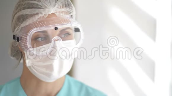 戴着医疗面罩护目镜和一次性帽子的护理人员的肖像视频的预览图