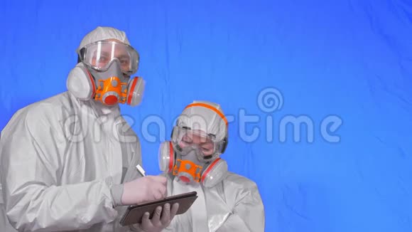 呼吸器的病毒学家用手写笔在平板电脑中写作穿着保护性衣服的男人和女人视频的预览图