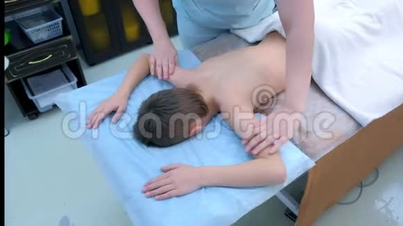 专业医生按摩师在诊所为背部脊柱的青少年男孩做按摩视频的预览图