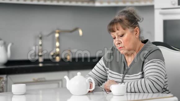 寂寞怅惘坐在桌上喝咖啡休息的老太太情绪低落视频的预览图