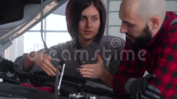 两名专业技工男女在汽车修理厂修理一辆汽车汽车服务维修和保养视频的预览图