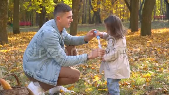 爸爸和小女儿在秋天公园吹气泡视频的预览图