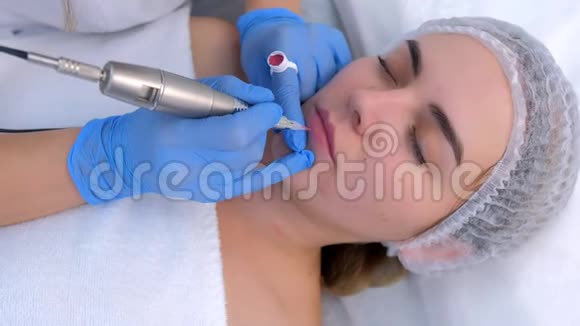 美容师在嘴唇上使用永久化妆使轮廓使用纹身机视频的预览图